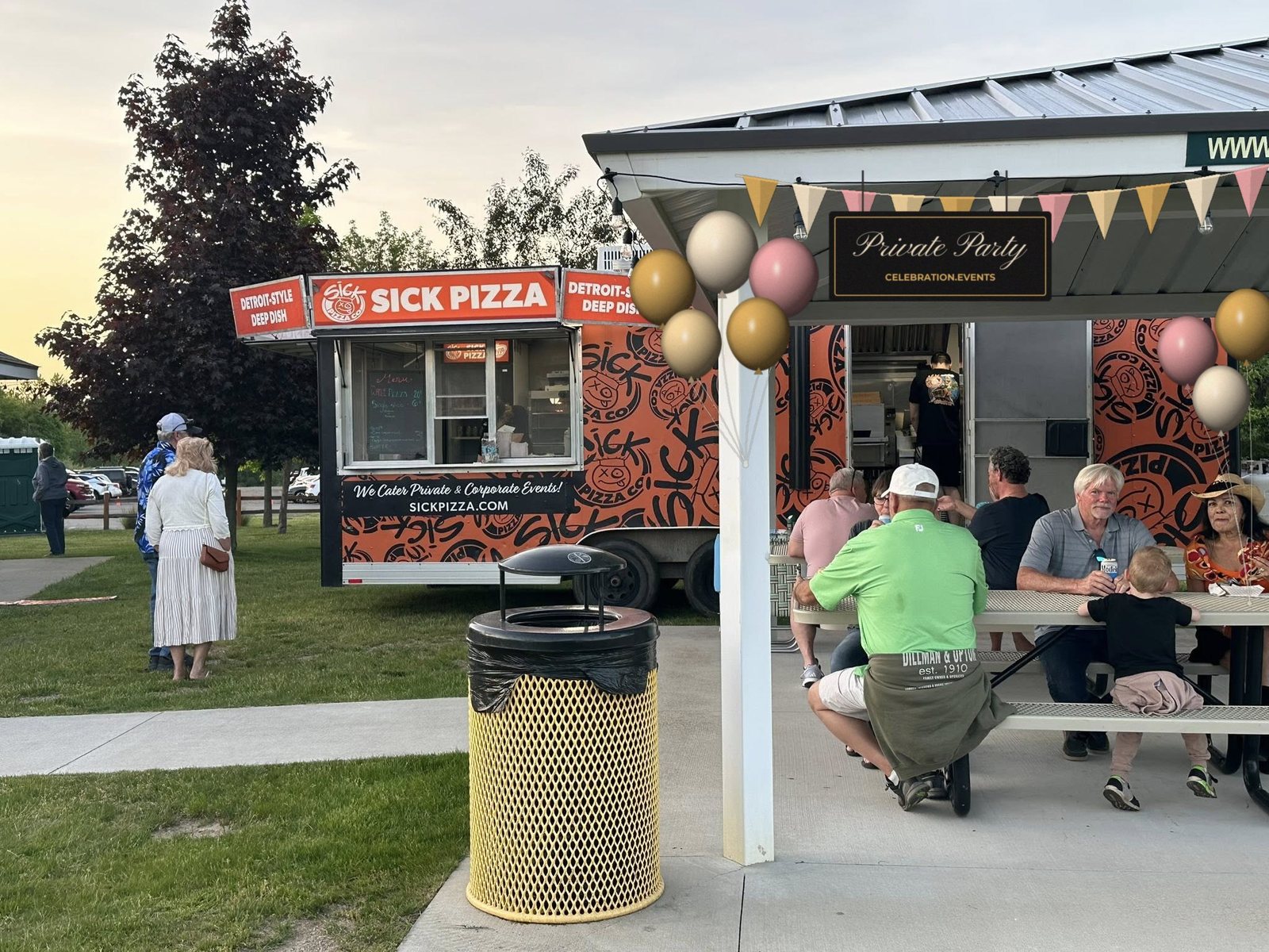 The Wildwood pavilion set for a private party with balloons, bunting and a Private Party sign, guests eating pizza